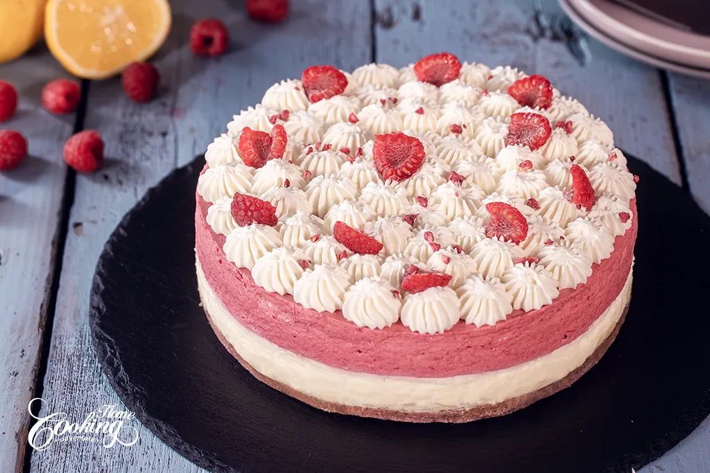 White Chocolate and Raspberry Mousse Cake decorated with Sweetened Whipped Cream and fresh raspberries