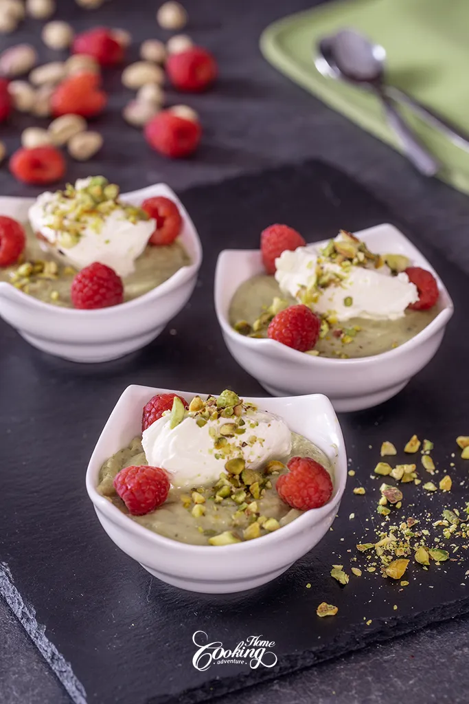 creamy pistachio pudding with whipped cream and fresh raspberries